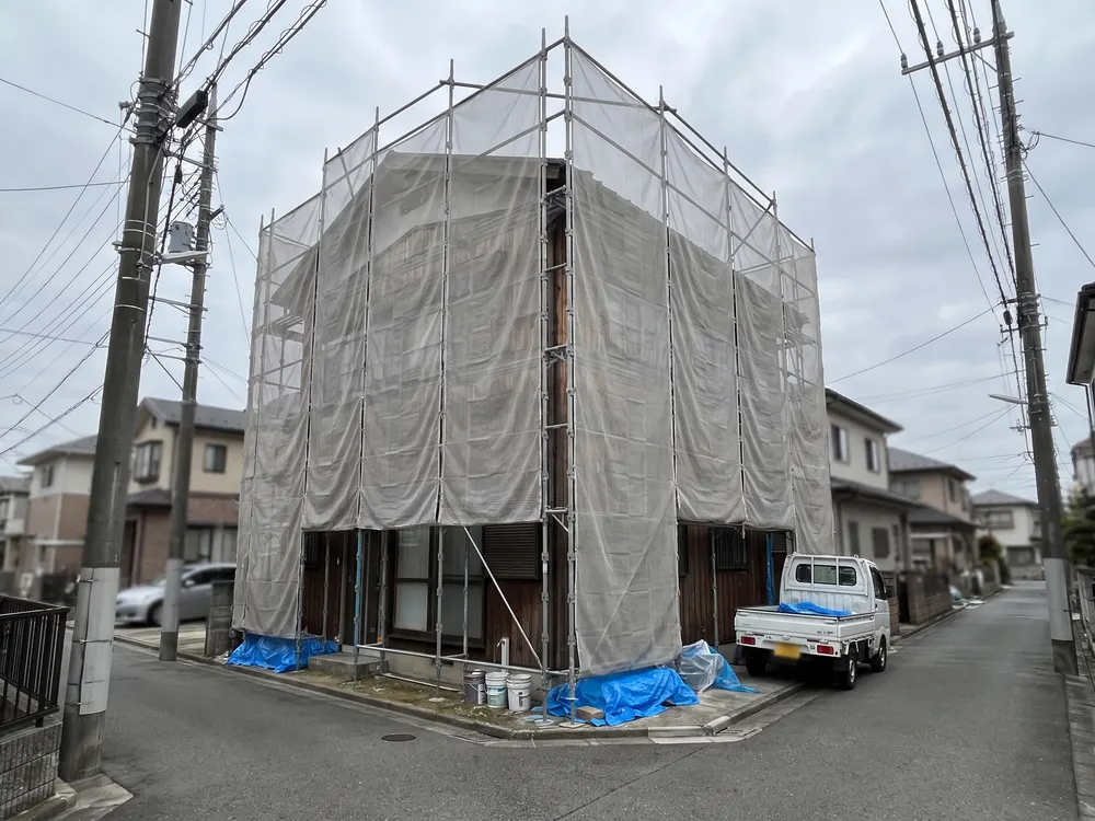 足場と白いシートで囲った工事中の家