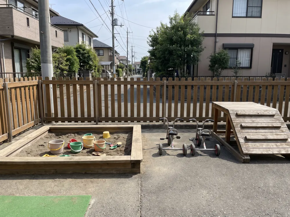 砂場と三輪車と木の坂のある園庭